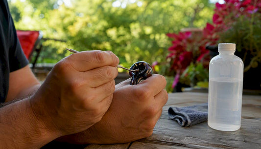 Hands scraping resin from glass pipe