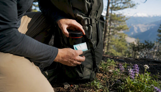 Hiker packing smell-proof cannabis container in backpack