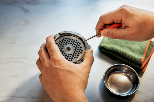 Hands loosening a stuck grinder screen